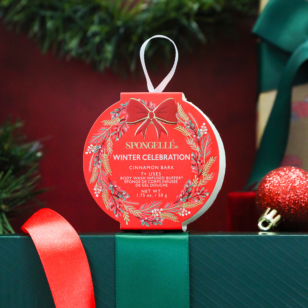 Spongellé Winter Celebration body buffer on a green gift box with festive background
